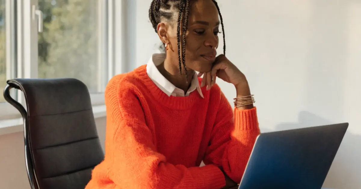 A business owner working thoughtfully at a laptop beside a bright window, in warm natural light